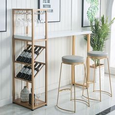 two stools sitting next to a table with wine glasses on it and a plant in the corner