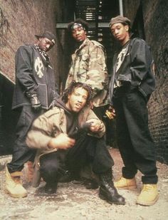 four young men standing in an alleyway with one pointing at the camera while another looks on