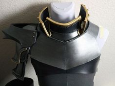 a mannequin is dressed in black leather with gold chains on it's neck