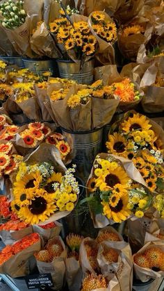 sunflowers and other flowers are on display in baskets