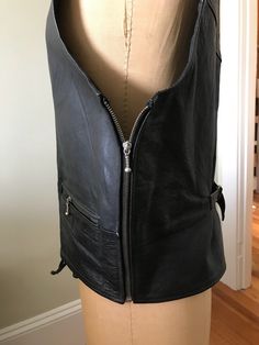 "Black leather hooded vest for either male or female. Imposing look to this leather vest would make a great addition to the heavy metal rocker musician's arsenal of stage wear. Industrial metal zippers and a laced up front closure are the design detail accents on this piece. Wedding attire perhaps for a Goth bridegroom! Hood zips up the back and can be removed as it snaps on or off. Top shoulder zippers and side entrance zippers on either side with a rear buckle to tighten or loosen. Made by 'Ri Gothic Black Leather Biker Jacket, Fitted Leather Vest For Streetwear, Fitted Black Rocker Vest, Black Fitted Rocker Vest, Edgy Black Vest For Biker Events, Sleeveless Biker Vest For Alternative Fashion, Gothic Leather Biker Jacket For Biker Events, Gothic Leather Biker Jacket For Events, Leather Biker Jacket For Cosplay