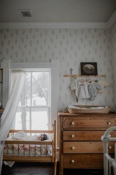 a baby's crib and dresser in a room with floral wallpaper on the walls