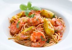 pasta with shrimp, zucchini and tomato sauce in a white bowl on a table