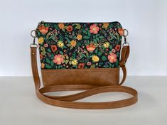 a floral print purse on a brown leather strap