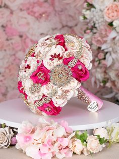 a bridal bouquet with pink and white flowers in front of a floral wallpaper