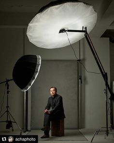 a man is sitting in front of a light on a tripod and posing for the camera