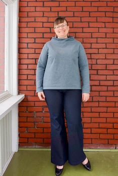 a woman standing in front of a red brick wall with her hands on her hips