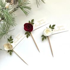 three red and white flowers on top of wooden sticks with merry christmas written on them