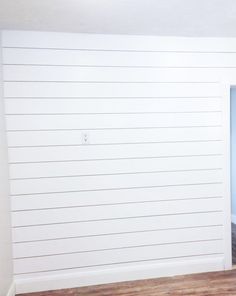 an empty room with white walls and wood flooring in the foreground is a blue door