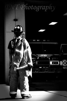 black and white photograph of a fireman standing in front of a building with his back to the camera