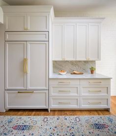 a kitchen with white cabinets and an area rug in front of the counter top that has a potted plant on it