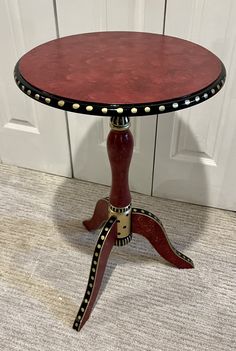 a small red table sitting on top of a carpeted floor next to a white door