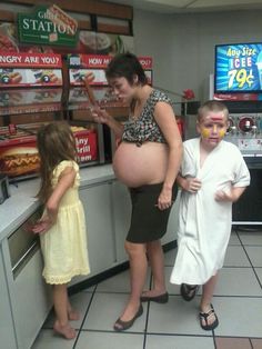 a pregnant woman and two children standing in front of a store counter with food on it