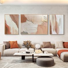 a living room with two paintings on the wall and a coffee table in front of it