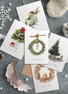 four christmas cards on a table next to some ornaments and a knitted mitt