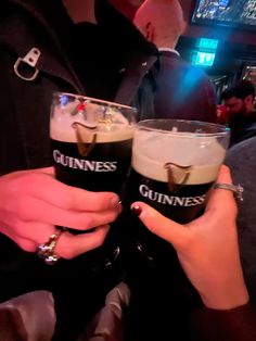 two people holding up guinness glasses in their hands