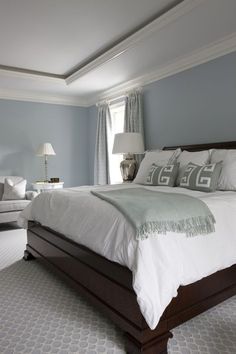 a bedroom with blue walls, white bedding and gray carpeted flooring is shown