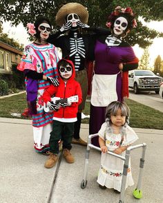 a group of people in costumes standing on the sidewalk with a child sitting on a crutch