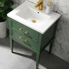 a bathroom sink sitting next to a green cabinet with gold faucets on it