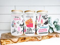 three personalized tumblers with stickers on them sitting on a wooden slab next to succulents