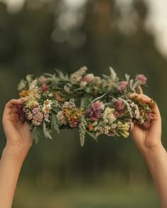 two hands holding flowers in the middle of each other's hands, with trees in the background