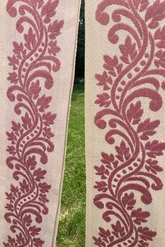 two curtains with red and white designs on them in the grass, one is closed