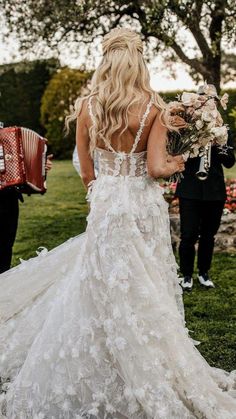 a woman in a wedding dress walking down the aisle with an accordian accordion behind her