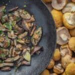 mushrooms and oranges are cooking in a skillet