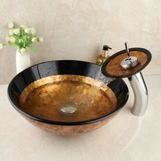 a black bowl sink sitting on top of a counter next to a vase with flowers