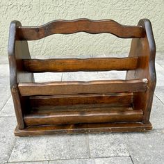 a wooden bench sitting on top of a stone floor next to a wall and sidewalk