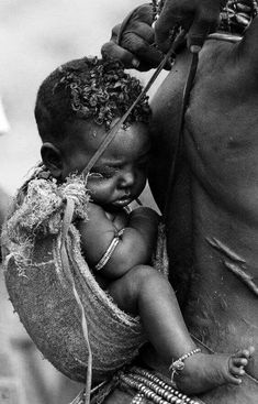 a black and white photo of a baby being held by an adult