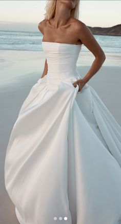 a woman in a white dress standing on the beach