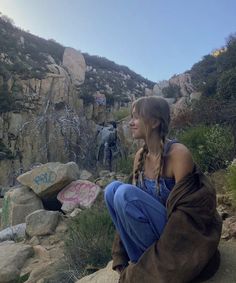 a woman sitting on top of a rock covered hillside