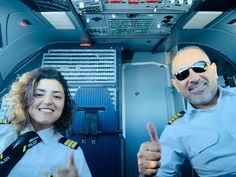 two pilots giving thumbs up in the cockpit of a plane