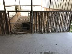 an animal pen with sheep in it next to a fence and dirt floored area