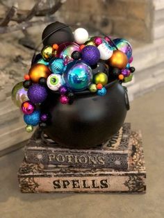 a black pot filled with lots of different colored ornaments on top of a pile of books