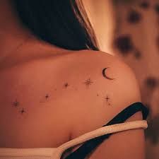 the back of a woman's shoulder with stars and moon tattoos