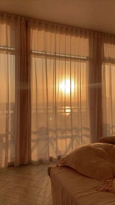 the sun is setting behind sheer curtains in this bedroom