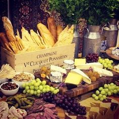 an assortment of cheeses, grapes and bread on a table