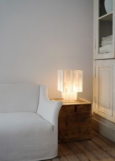 a white couch sitting next to a table with a lamp on it's side