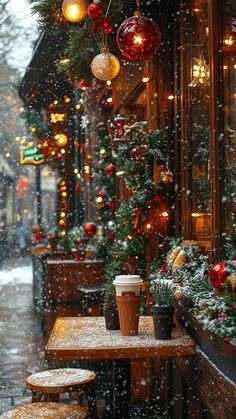 two cups of coffee sitting on top of a table in front of a building with christmas decorations