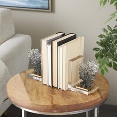 three books are sitting on a table next to a vase with silver flowers and leaves