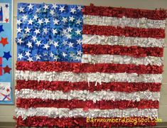 an american flag made out of red, white and blue tissue paper is hanging on the wall