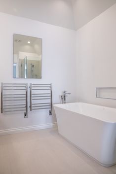 a white bath tub sitting under a bathroom mirror