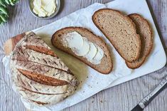 a loaf of bread sitting on top of a cutting board next to butter and knife