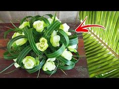 a bouquet of white flowers sitting on top of a wooden table next to a palm tree