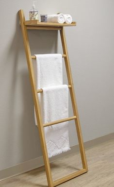 a wooden towel rack with two white towels on top and one folded in the shape of a ladder