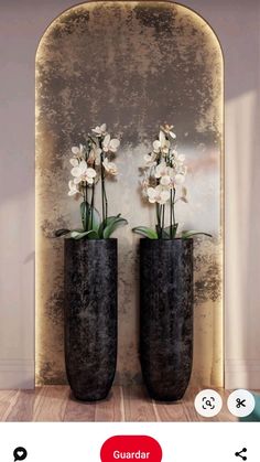 two black vases with flowers in them