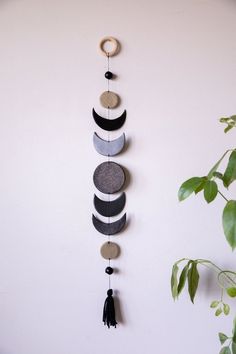 a wall hanging made out of stones and wooden circles with tassels on it