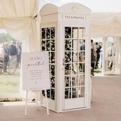 a white phone booth sitting in the middle of a field